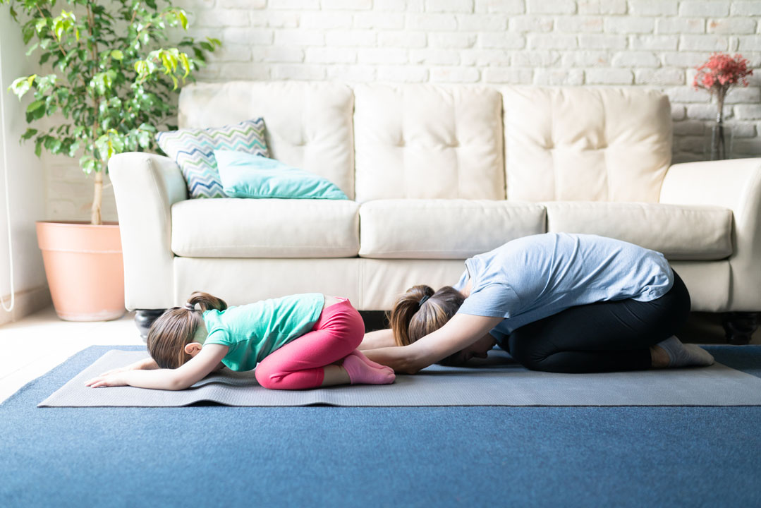 om and little girl doing child's pose - yoga - neck stretch