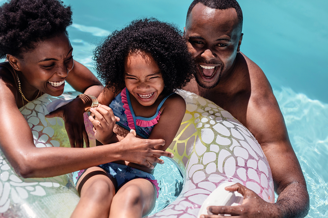 Black man and woman playing with their daughter in the pool - tracking macronutrients for weight loss