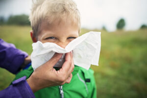 Mother cleaning the nose of a boy with a tissue - Seasonal allergies - AlignLife