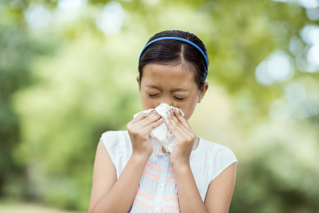 Girl blowing her nose with handkerchief while sneezing - seasonal allergies