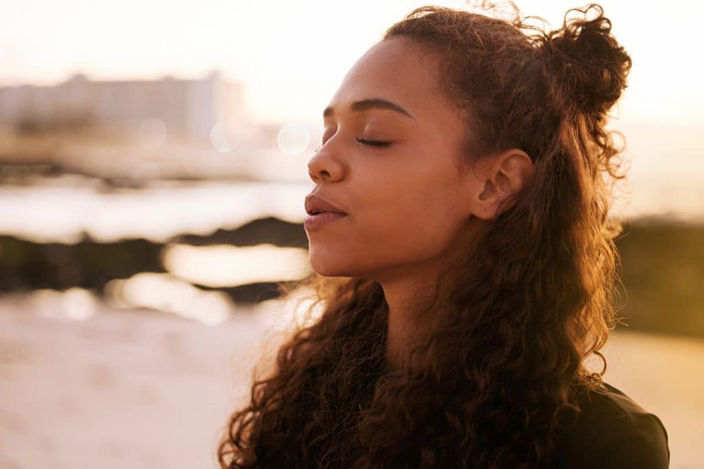 woman outdoors focusing on proper breathing techniques and meditation for better health