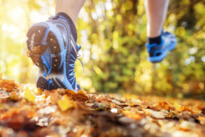 Trail running - close up of runners feet running through leaves - AlignLife