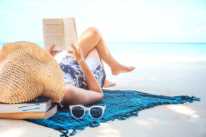 woman reading book on beach