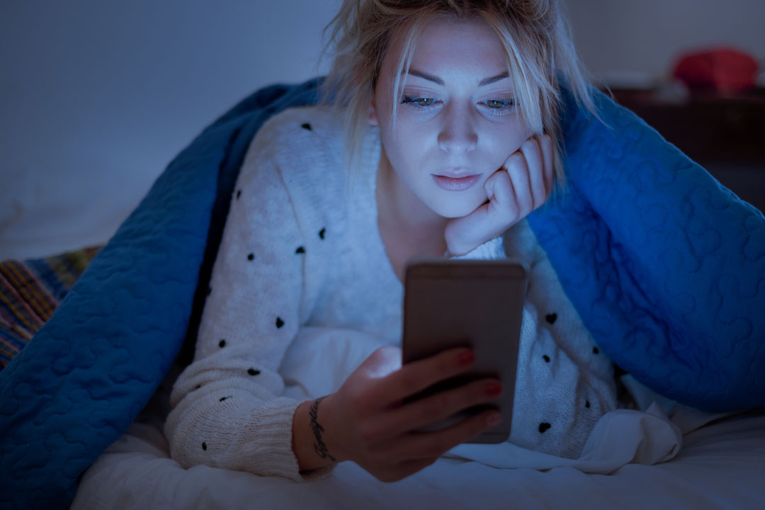 woman looking at blue light screen at night