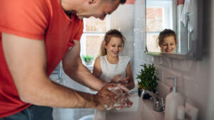 man and daughter washing hands in bathroom