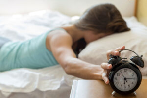 woman waking up stopping alarm clock