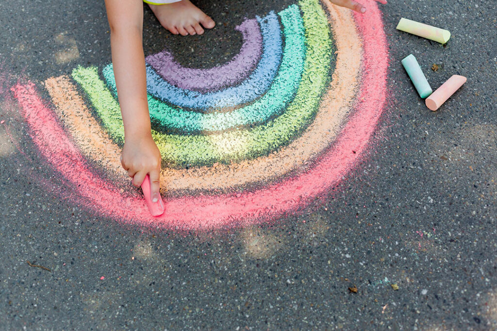 girl drawing rainbow with sidewalk chalk and sidewalk paint