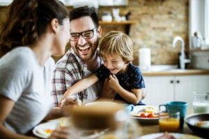 Man, wife and child - young cheerful family having fun at dining table.