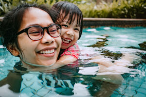 mom doing water exercises with child in swimming pool