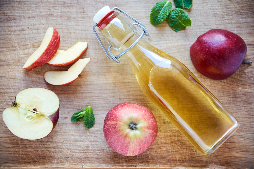 Overhead shot of a bottle of apple cider vinegar on a wooden table - mucus fighting food