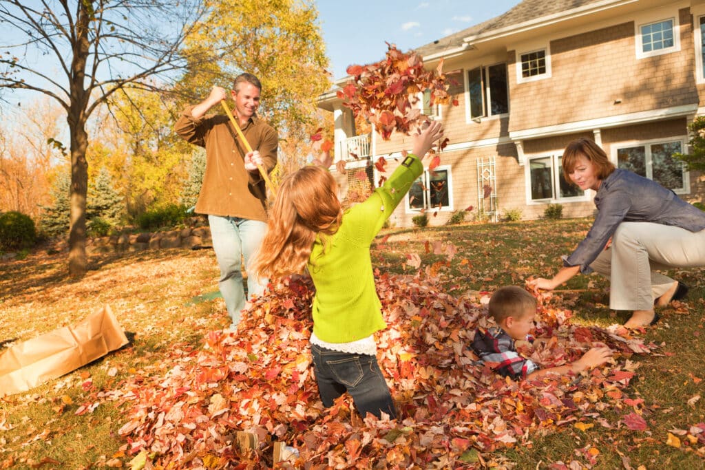 family raking leaves into a pile in the Fall