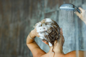 Back view of a woman washing her hair with a shampoo in bathroom