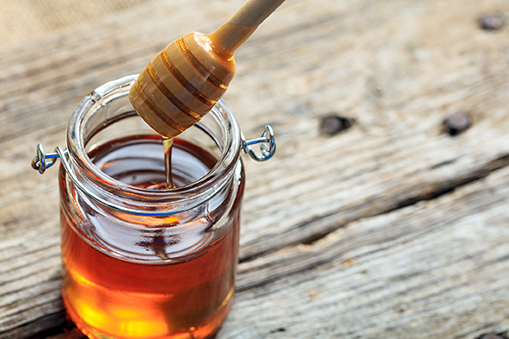 A glass jar with honey on a table - natural sweetener - sugars