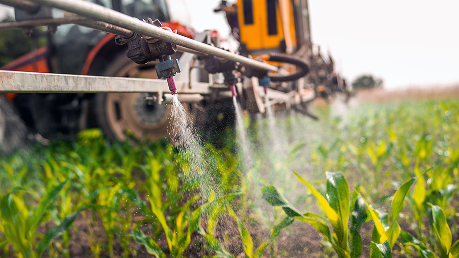 Crop sprayer spraying pesticides on crops in field - dirty dozen - clean fifteen - alignlife