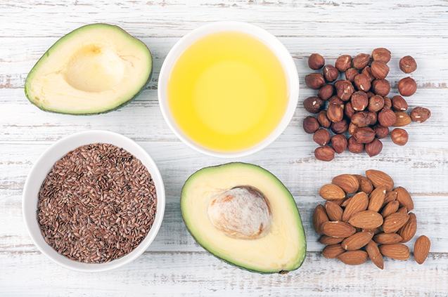 Foods with healthy fats. Sources of omega 3 - avocado, olive oil, nuts and flax seed on wooden background. Healthy food