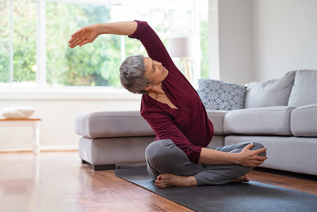 Morning yoga - side bending stretch - mature woman in living room