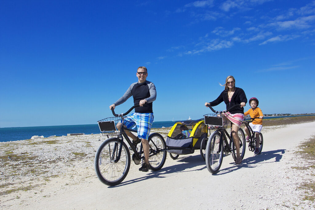 family riding bikes on beach