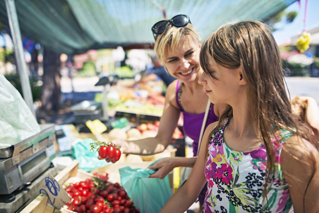 Mother and daughter buying tomatoes at the Italian farmer's market. Cecina. Italy, Tuscany.