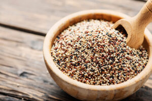 Uncooked quinoa in the wooden bowl, rustic style and selective focus