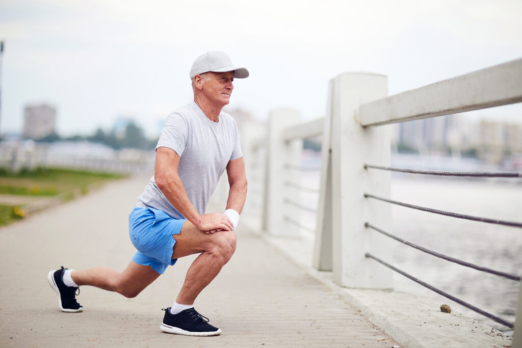 senior man stretching on boardwalk