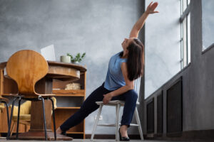 Woman practicing chair yoga at home