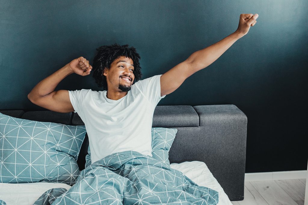 man stretching in bed after a good sleep