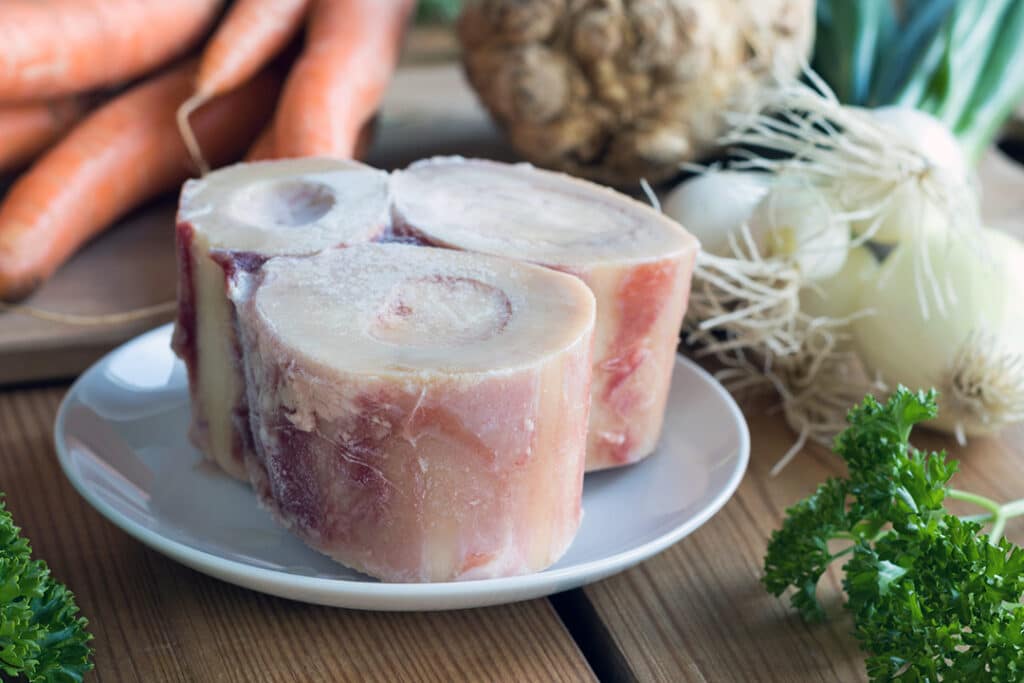 Ingredients for making a beef bone broth - marrow bones, carrots, onions, parsley, and celery root