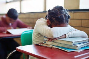 young girl sleeping at her desk in a classroom