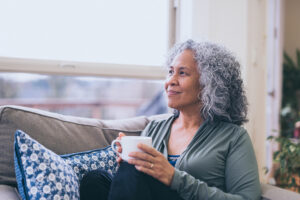 Hawaiian women looking out window with a cup of coffee - Magnesium for better moods