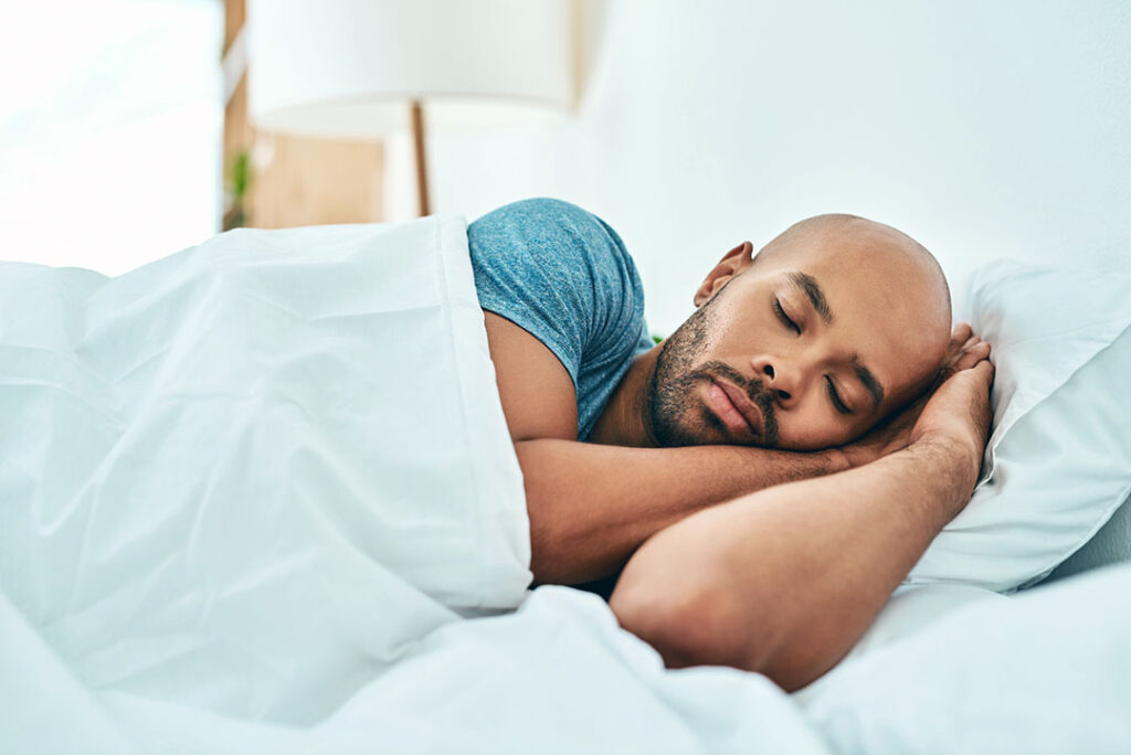 black man side sleeping in bed - back pain prevention sleep poses