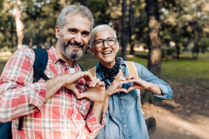 Mature couple on a trip in the nature showing hearts