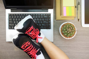 Business women laying her legs in sport shoes over the laptop, Life and work balance concept.