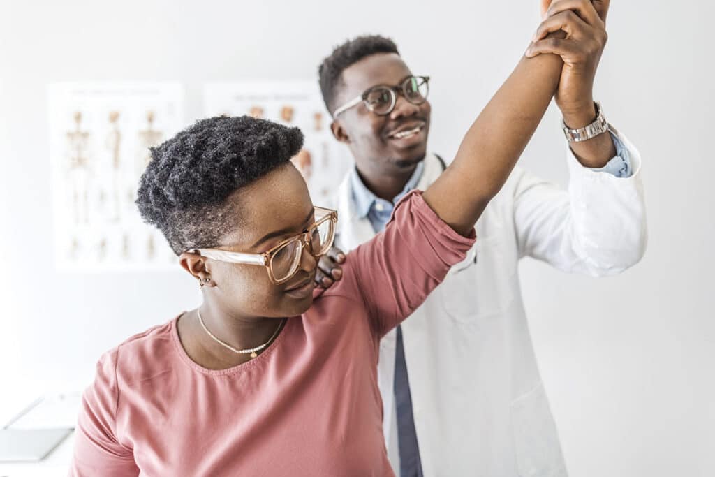 Young black woman at chiropractor doing mobility exercise movement function tests