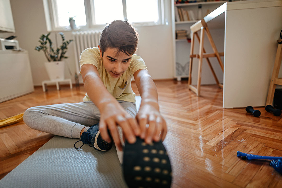 Teen boy student athlete stretching at home - back to school sports physical