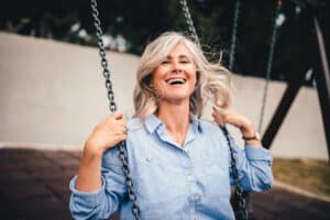 mature woman swinging on a swing - living young - high energy