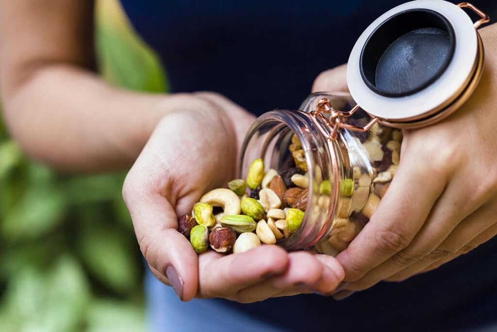 Woman holding jar of mixed nuts - snacks for energy