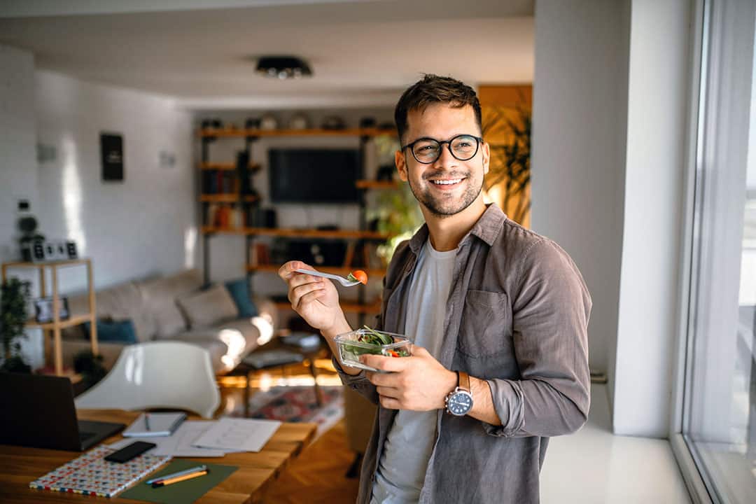 Man eating health salad at home - clean eating to lose weight