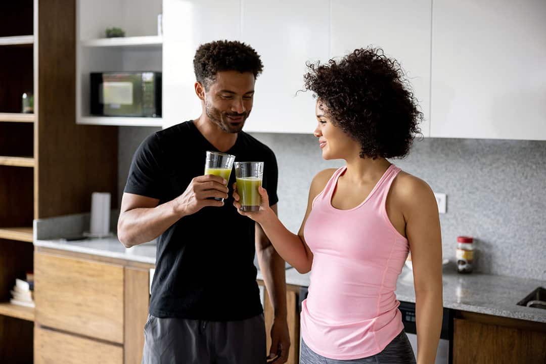 couple toasting to a health detox green smoothie