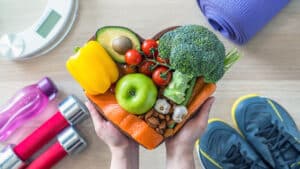 woman holding various fruits and vegetables in shape of a heart - nutrition for heart health - how to prevent heart disease