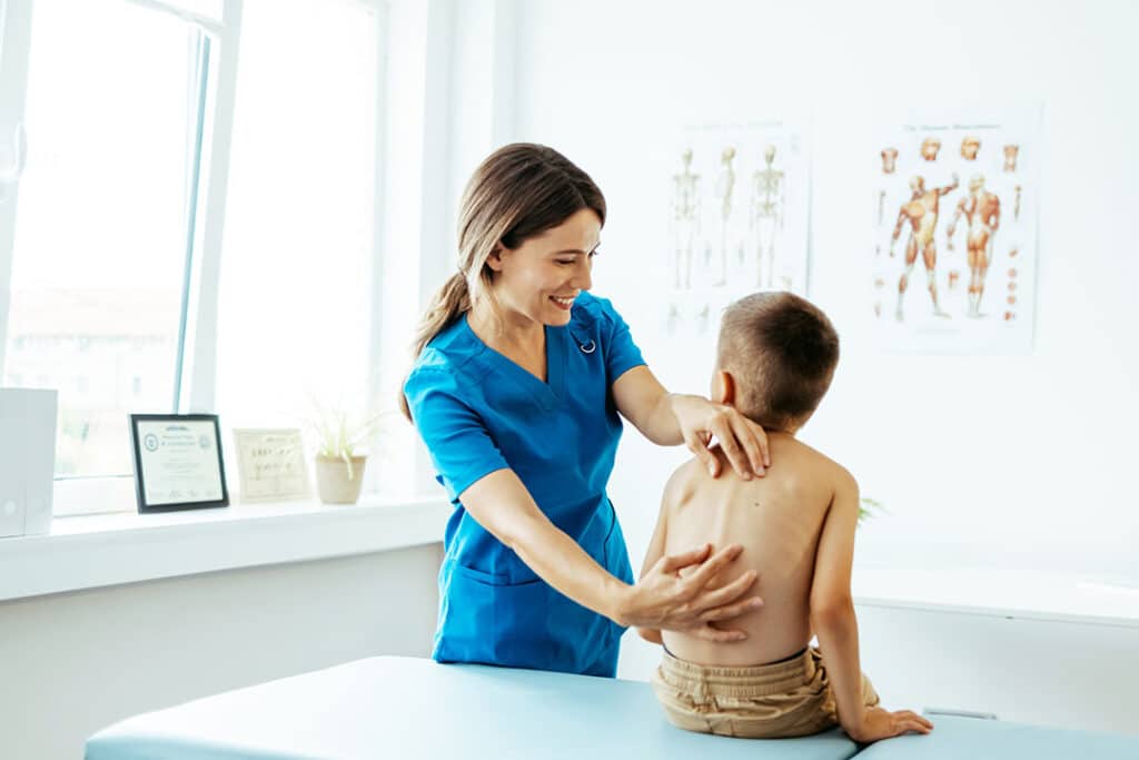 chiropractor examining child's spine - family chiropractic care