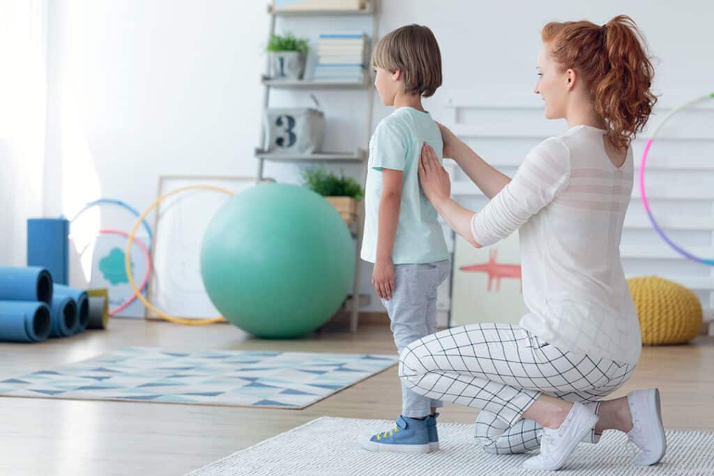 female chiropractor checking boy's spine