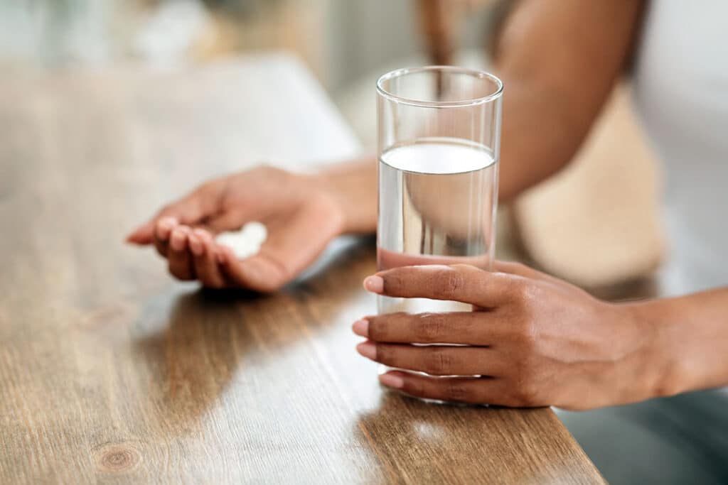 womaning holding a magnesium supplement and glass of water