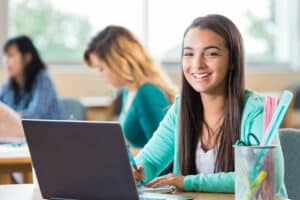 teenage girl sitting at school desk with good desk ergonomics and posture