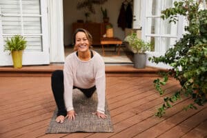 Mature woman stretching her hip flexors outdoors on the deck - exercises for low back pain relief