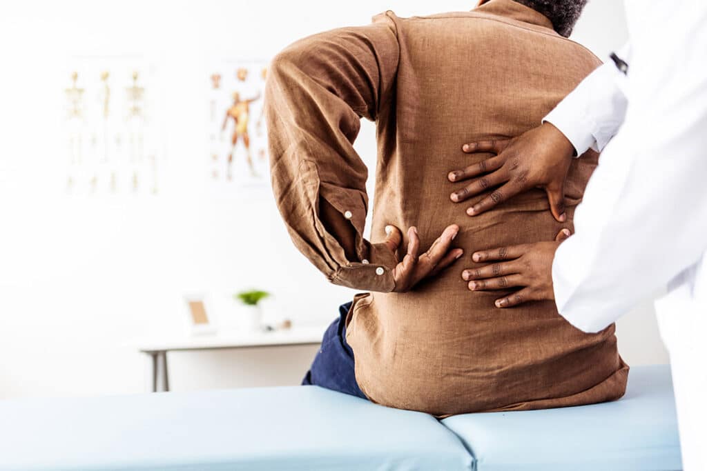 senior man working with chiropractor for low back pain