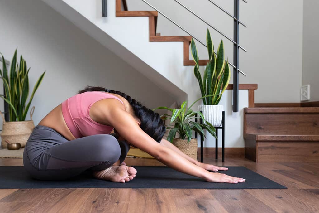 young woman doing yoga in her home - stretching for low back pain