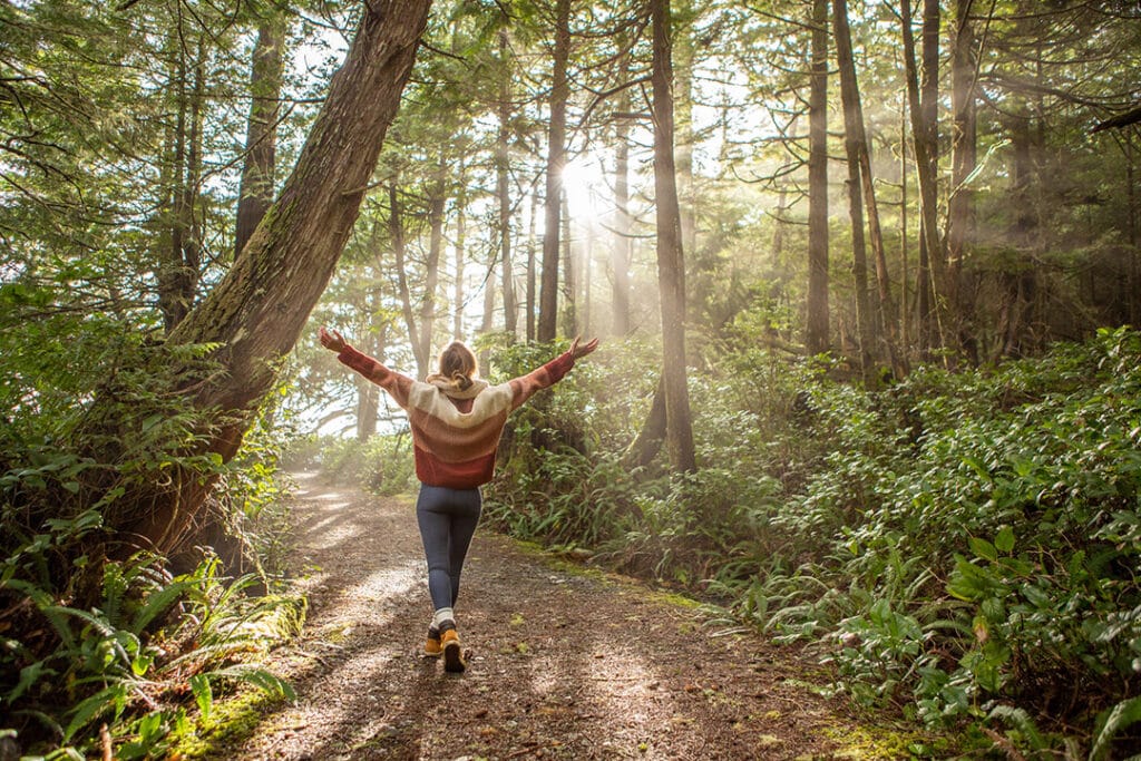 Young woman walking outdoors on hiking trail to recharge from burnout symptoms