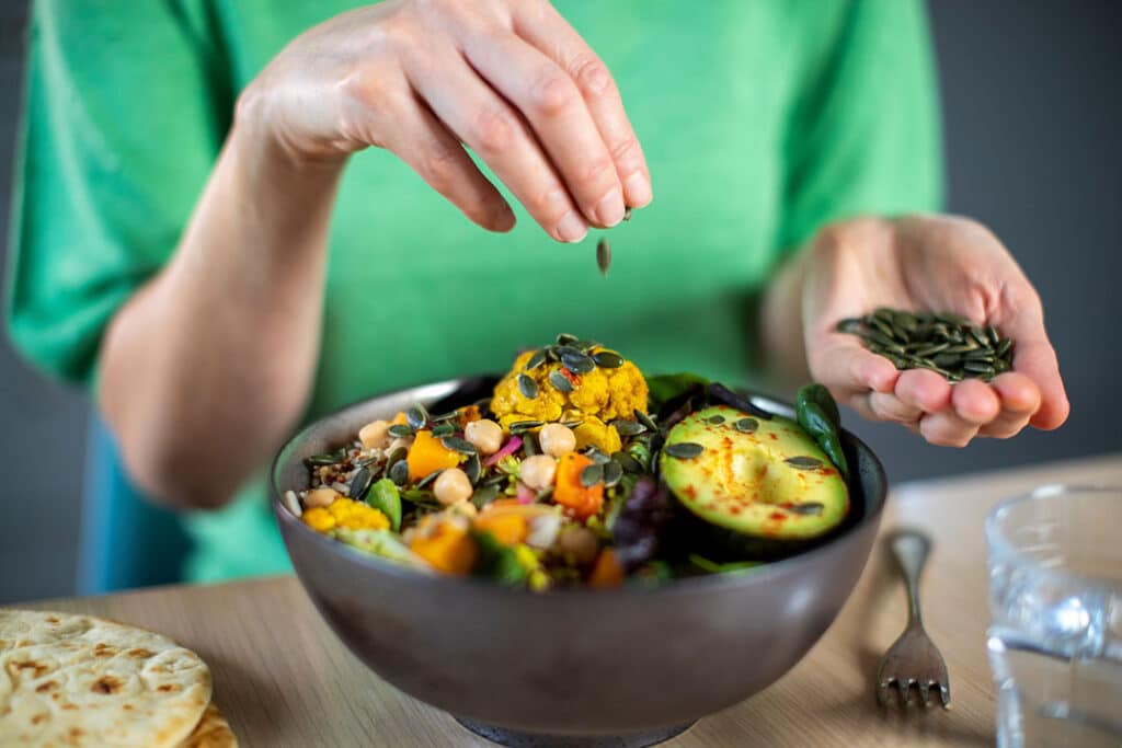 Woman adding pumpkin seed to meal - Way to Increase Serotonin levels naturally - AlignLife