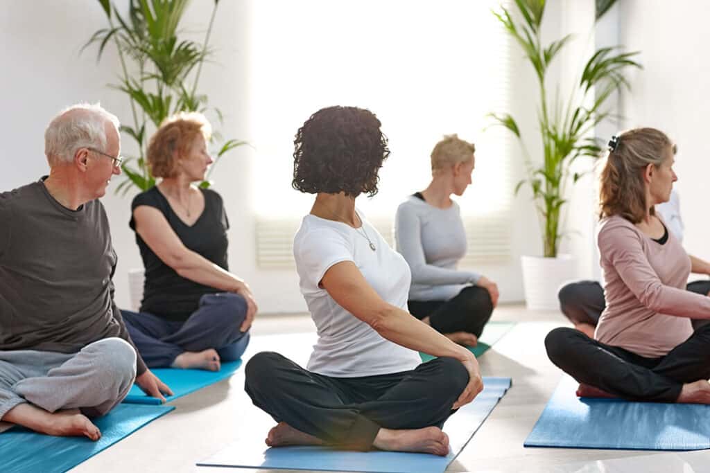 Group of mature men and woman practicing yoga in a health club - spine wellness - spine to symptoms - AlignLife