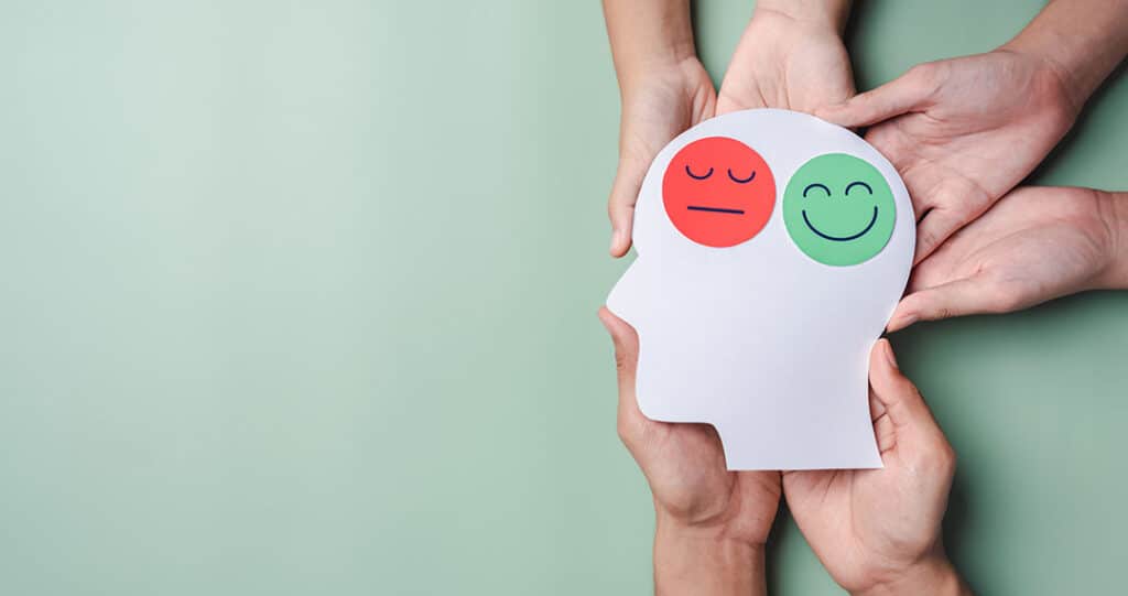 Hands holding sad face and happy smiley face on brain paper cut out, bipolar and depression, mental health, personality, mood change, - Managing Mood Swing or Changing Moods with AlignLife